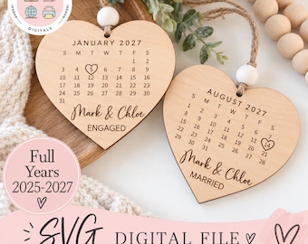 Può includere: Due ornamenti in legno a forma di cuore con calendari incisi per gennaio 2027 e agosto 2027. Il cuore di gennaio include il testo Mark & Chloe ENGAGED con una data cerchiata, mentre il cuore di agosto mostra Mark & Chloe MARRIED con una data cerchiata.