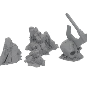 May include: A collection of gray miniature terrain pieces for tabletop gaming. Includes several rock formations and a skull with a weapon embedded in it. Ideal for fantasy or war game settings.