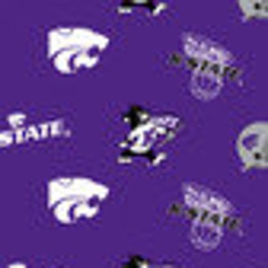 May include: Purple fabric with a repeating pattern of the Kansas State University Wildcats logo. The logo features a white wildcat head with a black outline and the words "K-State" in white.