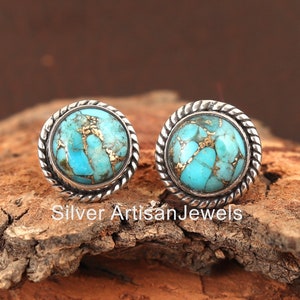 May include: A pair of silver earrings with turquoise stones. The stones have a marbled pattern with gold flecks. The earrings have a rope-like design around the edge.