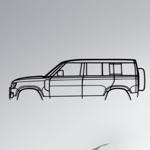 Puede incluir: Un contorno de coche negro de metal está montado en una pared blanca sobre un sofá gris con almohadas. El sofá está en un salón con una mesa de café y una lámpara de pie.
