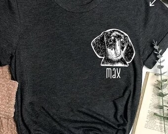 Puede incluir: Una camiseta gris oscuro con una ilustración blanca de un perro salchicha y el nombre "Max" impreso en la parte delantera.
