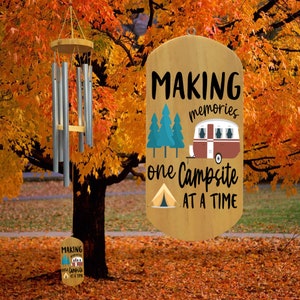 Peut inclure: Panneau en bois avec le texte "MAKING memories one Campsite AT A TIME" avec un camping-car et une tente. Le panneau est suspendu à une branche d'arbre avec des feuilles d'automne.