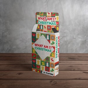 Puede incluir: Una caja de cartas de juego "What Am I? Christmas". La caja est&aacute; decorada con un patr&oacute;n navide&ntilde;o colorido y presenta un mu&ntilde;eco de nieve, un reno y otros iconos festivos. El texto "What Am I? Christmas" est&aacute; impreso en la parte delantera de la caja.