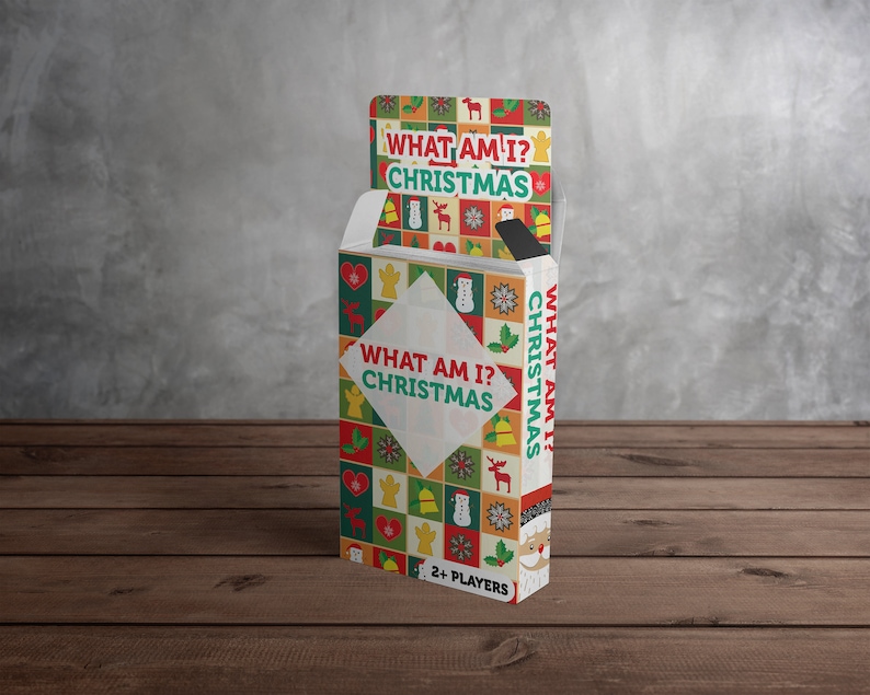 Puede incluir: Una caja de cartas de juego "What Am I? Christmas". La caja est&aacute; decorada con un patr&oacute;n navide&ntilde;o colorido y presenta un mu&ntilde;eco de nieve, un reno y otros iconos festivos. El texto "What Am I? Christmas" est&aacute; impreso en la parte delantera de la caja.