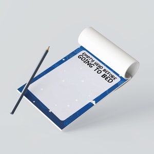 May include: A notepad with a blue border and the text "EMPTY HEAD BEFORE GOING TO BED". The notepad has a white background with star and cloud designs. A gray pencil rests on the notepad.