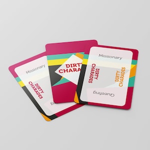 May include: Three game cards with rounded corners are fanned out against a white background. The cards have a white background with the words "Missionary" and "Dirty Charades" printed on them. The center card has a geometric design with the words "Dirty Charades".