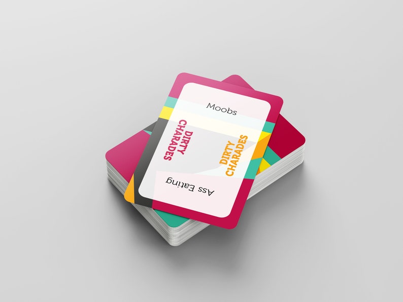 May include: A stack of playing cards with a pink and white design. The top card has the words "Moobs", "Dirty Charades", and "Ass Eating" printed on it. The cards have a colorful geometric design on the edges.
