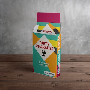 May include: A colorful box of "Dirty Charades" party game. The box features a geometric design with teal, yellow, orange, and pink colors. The game title and a film camera icon are displayed on the front. The text "Act Out or Lose Out!" is also visible.