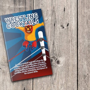 May include: A book titled "Wrestling Cocktails" featuring a cartoon wrestler on a blue background with red and blue lines. The book is on a wooden surface.