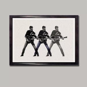 May include: A black and white photo of a man playing a guitar. The man is wearing a leather jacket and jeans. The photo is framed in a black frame.