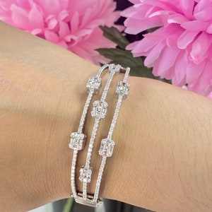 May include: A silver bracelet with four rows of sparkling diamonds. The bracelet features square-shaped diamonds set in a cluster design.