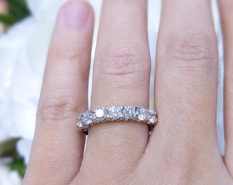 May include: A silver band ring with a row of round, clear diamonds.