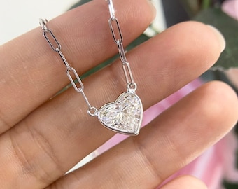 Puede incluir: Un collar de cadena de plata con un colgante de diamante en forma de corazón.