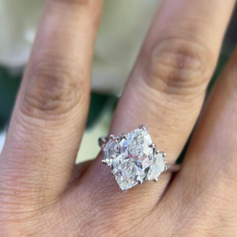 Woman wearing natural marquise shape diamond ring with cadillac shape diamonds on each side.