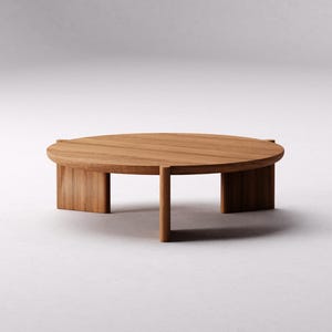 May include: A round wooden coffee table with a natural wood finish and four legs. The table has a simple, modern design.