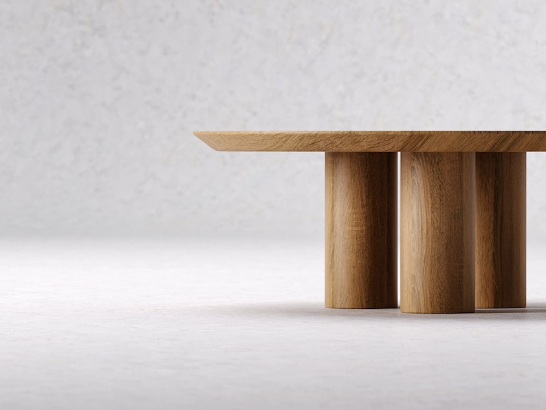 May include: A light brown wooden coffee table with a rectangular top and three cylindrical legs. The table is made of solid wood and has a natural finish. The design is minimalist and modern.