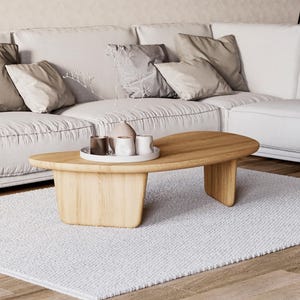 May include: A contemporary living room with a white sofa and cushions. A wooden, oval coffee table, approximately 120 cm long, rests on a white rug. Decorative items are on the table.