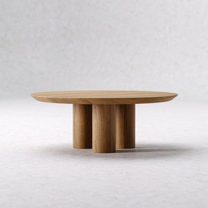 May include: A round wooden coffee table with a light brown finish. The table has a smooth, flat top and is supported by three cylindrical legs. The design is minimalist and modern, suitable for living rooms or lounges.