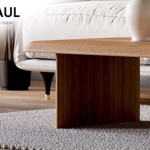 K&ouml;nnte beinhalten: Ein Holz-Couchtisch mit einer rechteckigen Tischplatte und einem einzigen, dicken, rechteckigen Bein. Der Tisch steht auf einem hellgrauen Teppich. Der Tisch ist mit "PAUL Coffee table" beschriftet.