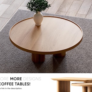 May include: A round wooden coffee table with a light brown finish and four legs. The table is sitting on a grey rug.