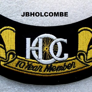 May include: A black embroidered patch with gold lettering and a white wheel design. The patch reads "H.C. 10 Year Member".