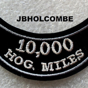 May include: Black motorcycle patch with white embroidered text that reads "10,000 HOG MILES".