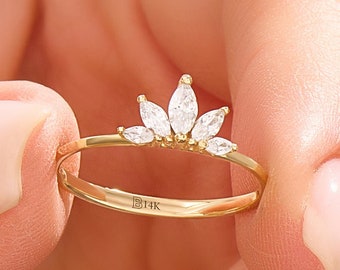 May include: A delicate gold ring with a crown of small, clear marquise-shaped diamonds. The ring is marked "14K" on the band.