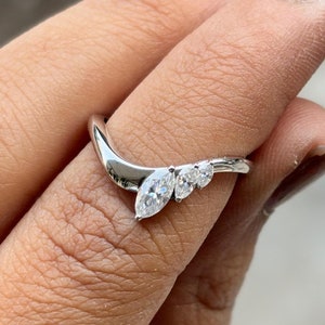 May include: A silver ring with three marquise-shaped diamonds set in a curved band.