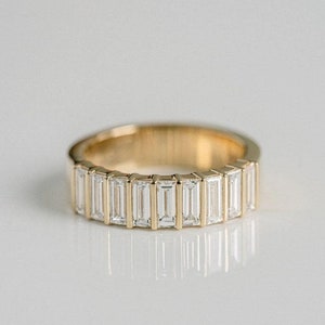 May include: A gold band ring with a row of baguette-cut diamonds.