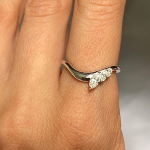 May include: A white gold ring with a curved band and three marquise-shaped diamonds.