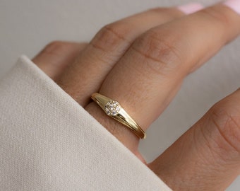 May include: A gold ring with a small cluster of clear stones set in the center.