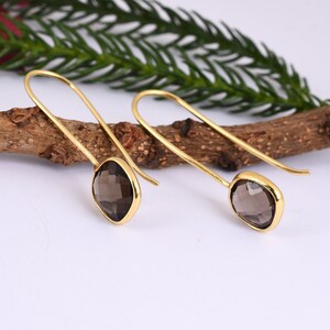 May include: A pair of gold-toned earrings with smoky quartz gemstones. The earrings have a simple, elegant design and are perfect for everyday wear.