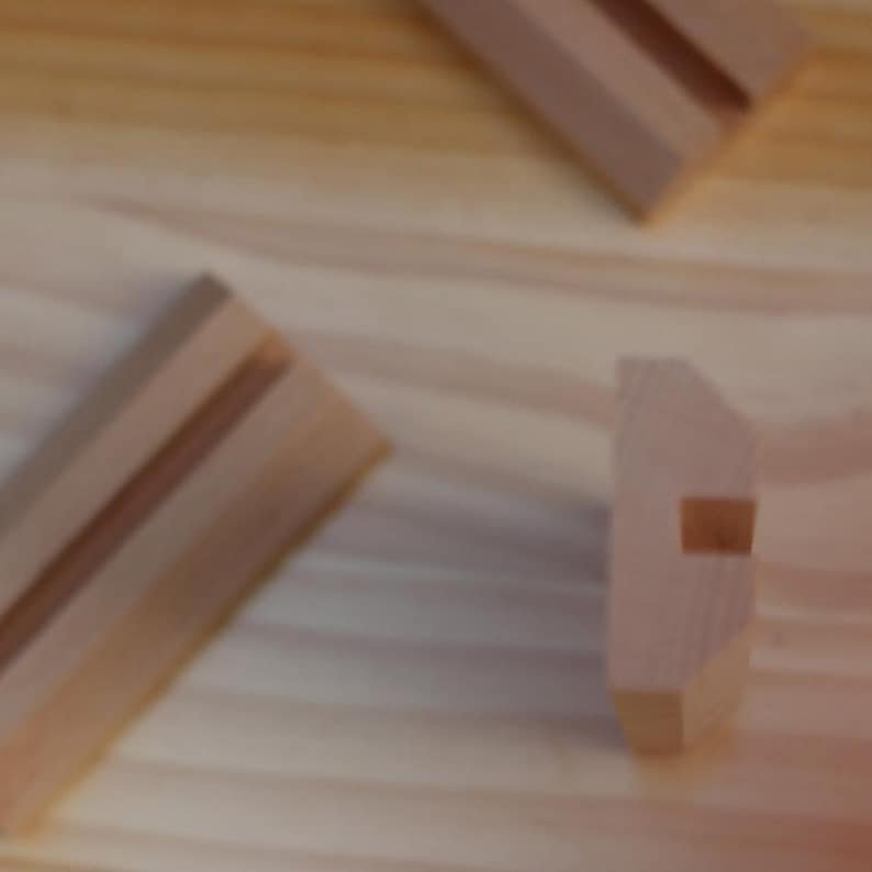 May include: Three wooden blocks with a groove cut into the top of each block. The blocks are made of light brown wood.