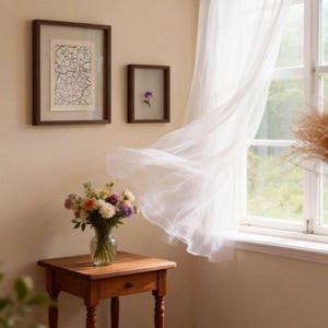 May include: A wooden side table holds a glass vase filled with a colorful bouquet of flowers. On the wall above, two dark-framed pictures hang, one with a black and white line drawing and the other with a single pressed purple flower.