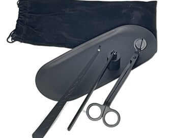 Könnte beinhalten: Ein schwarzes Kerzenlöscher-Set mit einem Tablett, einer Schere und einem Docht-Trimmer. Die Werkzeuge sind auf einem schwarzen Tablett mit einem Samtbeutel angeordnet.