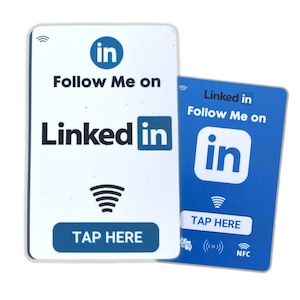 May include: Two rectangular white and blue cards with the LinkedIn logo and the text "Follow Me on LinkedIn". The cards have a tap-to-connect symbol and the words "Tap Here". One card is white, the other is blue.