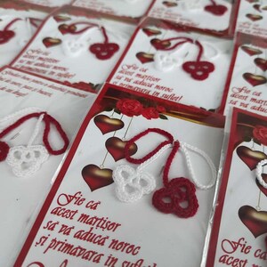 May include: A close-up of several red and white crocheted cherry charms with a message card that reads "Fie ca acest martisor sa va aducă noroc si primavara in suflet!"  The cards are packaged in clear plastic bags.