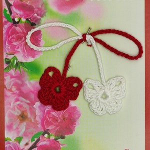 May include: A greeting card with a crocheted red and white flower charm. The card has a pink floral background and the text "Martie" and "Fie ca bucuria primaverii sa va cuprinda si sa va insoțească tot anul!"