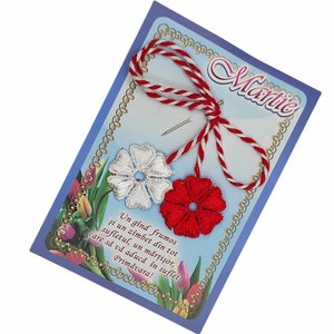 May include: A red and white string with a white flower and a red flower attached. The string is tied in a bow and the flowers are embroidered. The card reads "Martie" and "Un gînd frumos și un zîmbet din tot sufletul, un mărţişor, care să vă aducă în suflet Primăvara!"