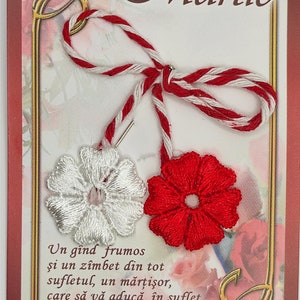 May include: A red and white martisor, a traditional Romanian charm, with a white embroidered flower and a red embroidered flower. The text on the card reads "Un g&icirc;nd frumos şi un z&icirc;mbet din tot sufletul, un mărţişor, care să vă aducă &icirc;n suflet Primăvara!"