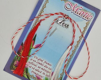 Pode incluir: Um cordão vermelho e branco com um amuleto de prata que diz "Love". O cordão está amarrado a um cartão com a palavra "Martie" nele. O cartão também tem o texto "Un gînd frumos şi un zîmbet din tot sufletul, un mărţişor, are să vă aducă în sufie Primăvara!"