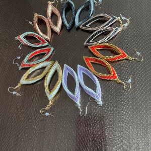 May include: A set of eight pairs of beaded earrings in various colors, including red, gold, white, black, and purple. The earrings are all in the shape of a teardrop with a small hole at the top for the earring hook.