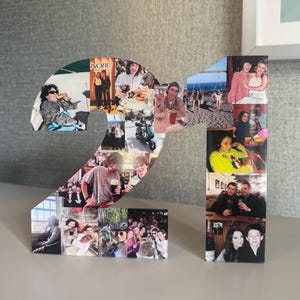 Puede incluir: Un número 21 de madera, lleno de varias fotografías. Las fotos son de personas en diferentes entornos, incluidos restaurantes, lugares al aire libre y reuniones informales. El número se muestra sobre una superficie de color claro.