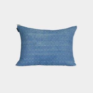 Op de afbeelding: Een rechthoekig blauw kussen met een herhalend patroon van kleine, lichtgekleurde ruitvormen. Het heeft een ritssluiting. Het ontwerp is eenvoudig en elegant, geschikt voor interieurdecoratie. Het kussen is waarschijnlijk gemaakt van stof.