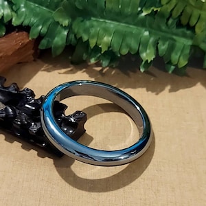 May include: A black hematite bangle bracelet with a polished finish.