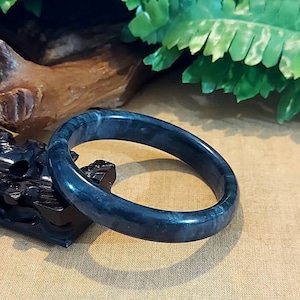 May include: A dark blue jade bangle bracelet with a smooth, polished finish.