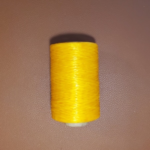 May include: A spool of bright yellow thread.