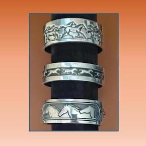 May include: Three silver-toned cuff bracelets with horse designs. The top bracelet features multiple horses in a running scene. The middle bracelet has a repeating pattern of running horses. The bottom bracelet showcases two horses' heads.