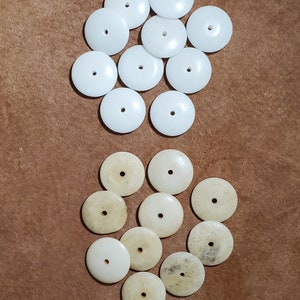 以下が含まれることがあります： 丸い白い骨のボタンが2つのグループに分かれています。上のグループには「Bone」とラベル付けされ、下のグループには「Antique Bone」とラベル付けされています。